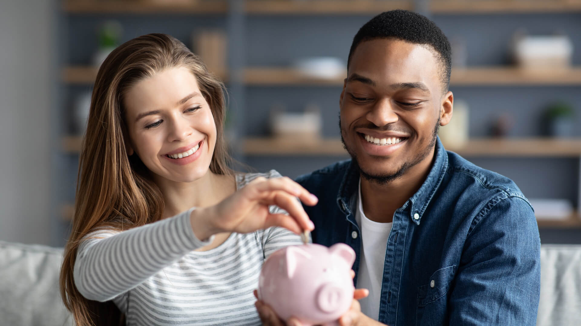 Ein Paar wirft Geld in eine Sparbüchse